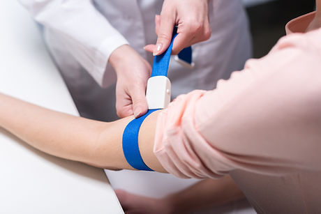 Medical professional applying tourniquet to patient's arm for blood draw